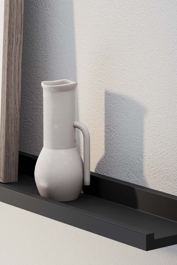 A close-up of a picture frame and ceramic jug on a 60'' black LAGOS floating ledge against a white textured wall