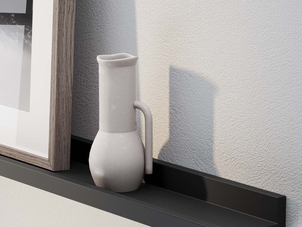 A close-up of a picture frame and ceramic jug on a 60'' black LAGOS floating ledge against a white textured wall