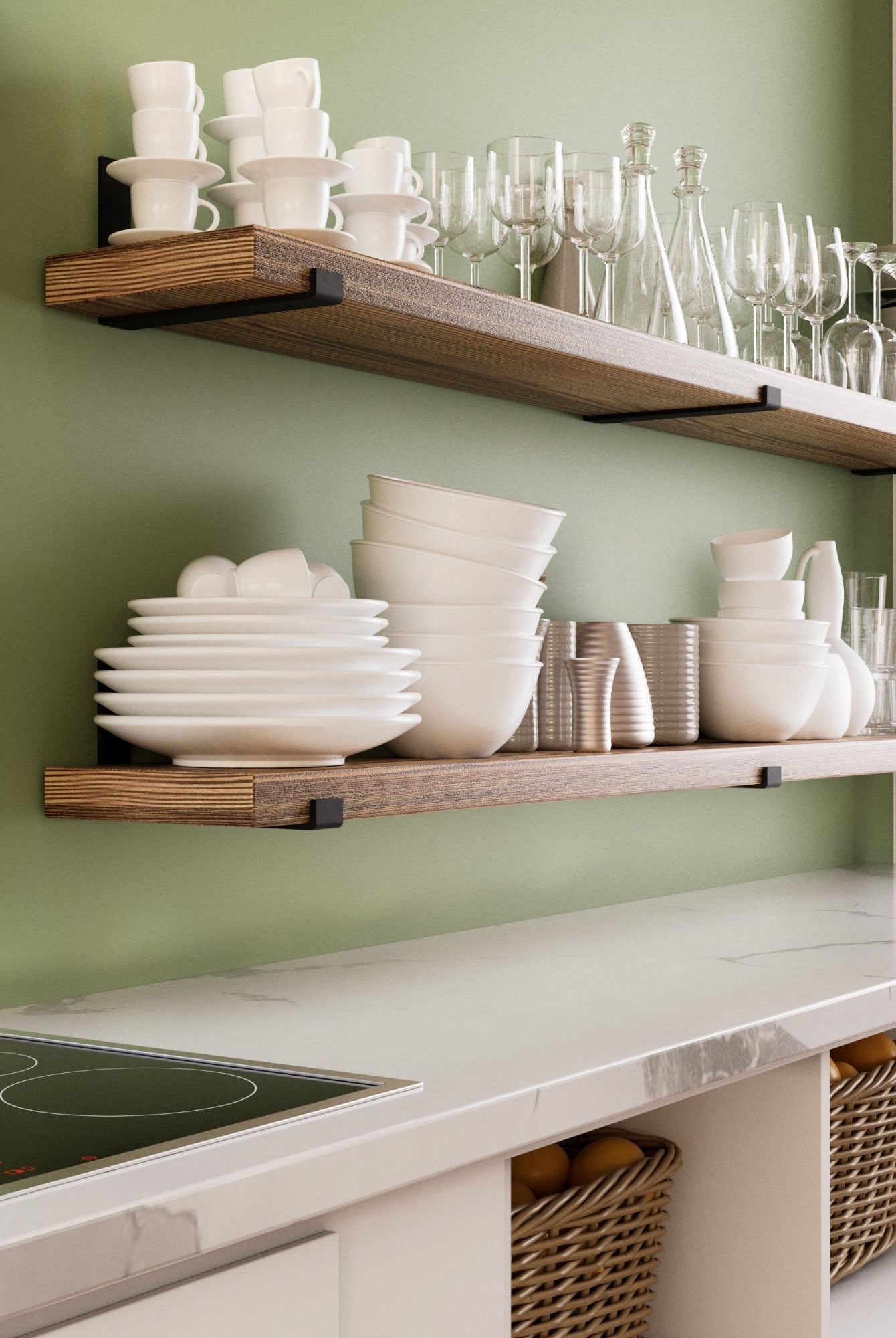 A stylish kitchen with two wooden floating shelves mounted on a sage green wall. The shelves hold neatly stacked white dishes, glasses, and cups. Below, a marble countertop with woven baskets adds warmth and organization.