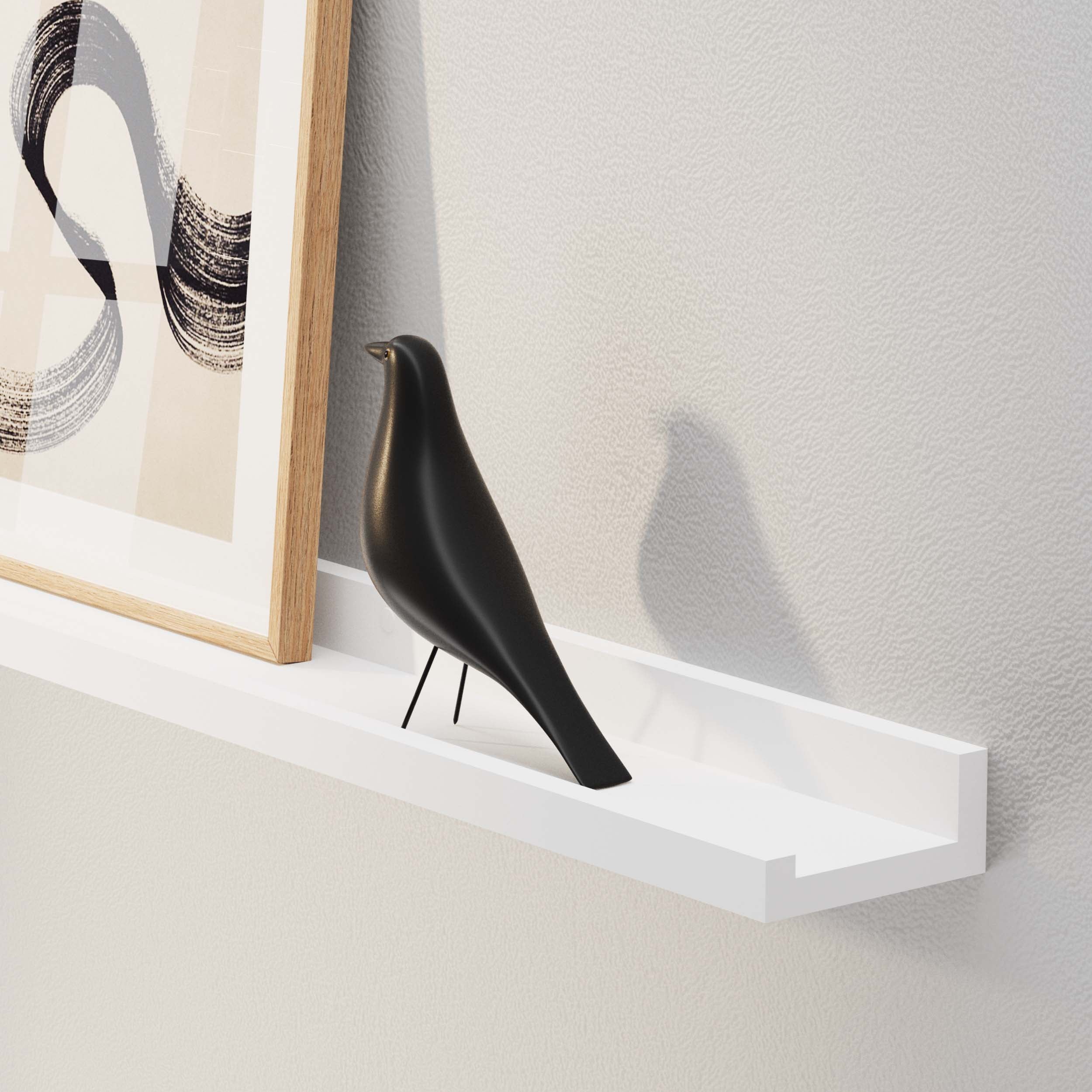 A sleek black bird figurine on a white floating shelf, casting a shadow, next to a framed abstract art piece.