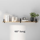 A 48-inch-long farmhouse display shelf mounted on a gray wall, featuring a minimalist arrangement of books, a plant, a clock, and decorative accents, with soft lighting enhancing the aesthetic appeal.