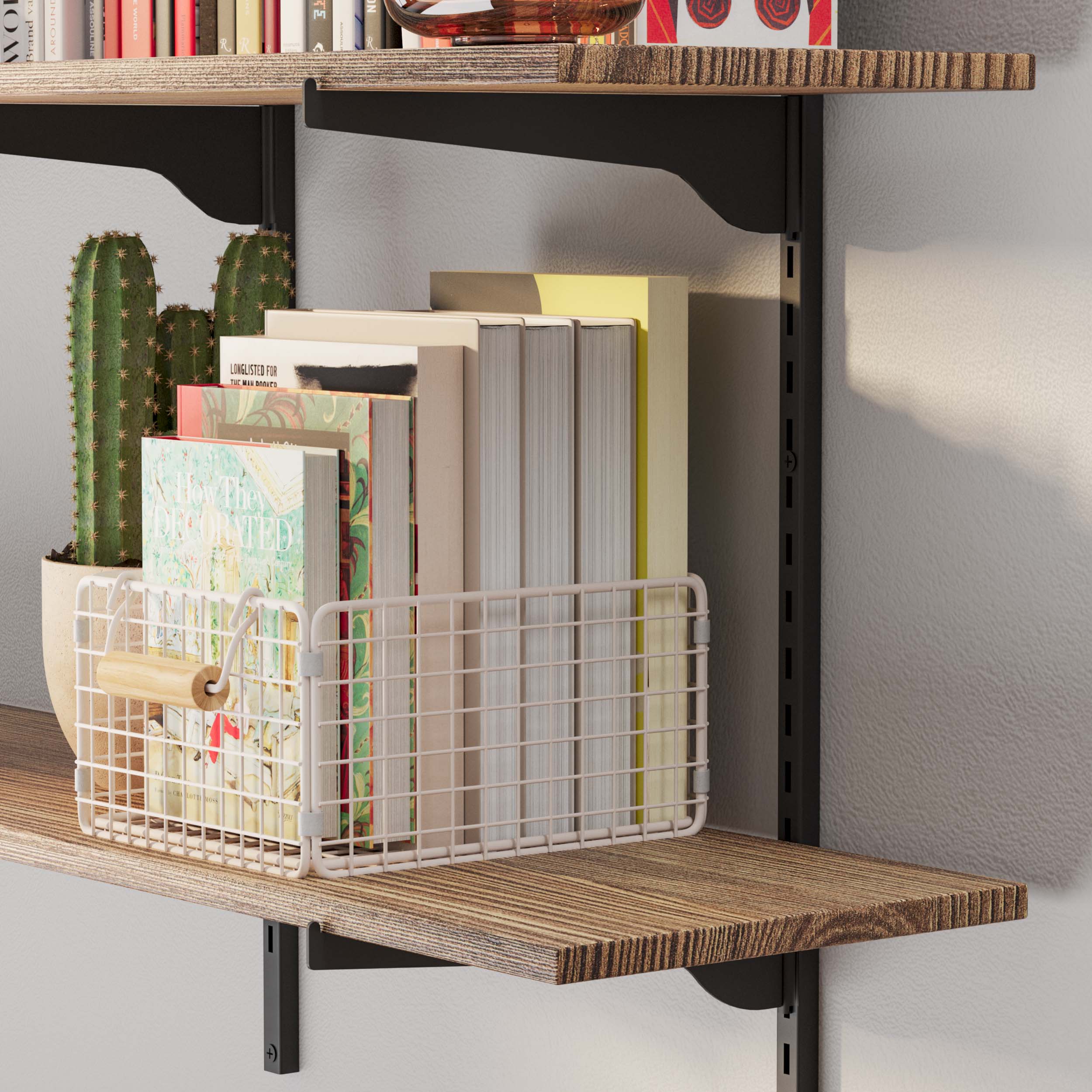 Close-up of a burnt wall mounted shelf with a cactus and a wire basket holding books, showcasing the textured wood surface and black brackets.