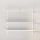 A plain view of empty white shelves with metal brackets on a light wall.