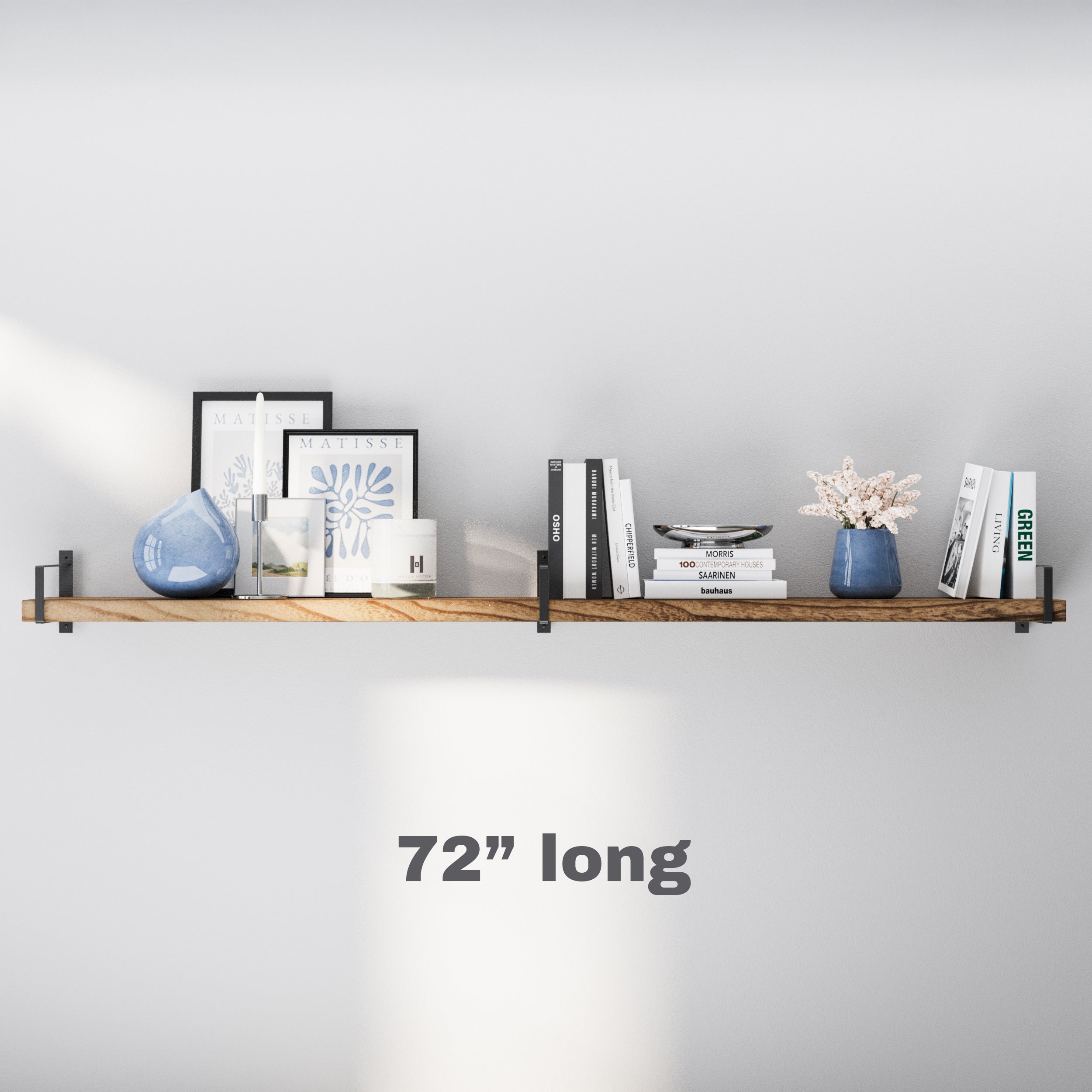 A 72” long floating shelf for storage in a warm wood finish, mounted with black metal brackets. Styled with minimal books, candles, and ceramic decor, perfect for adding functional elegance to any room.