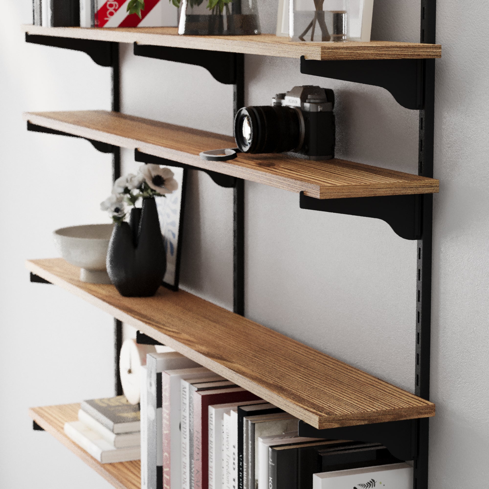 Wooden wall shelves with books, a camera, and decorative items against a white wall.