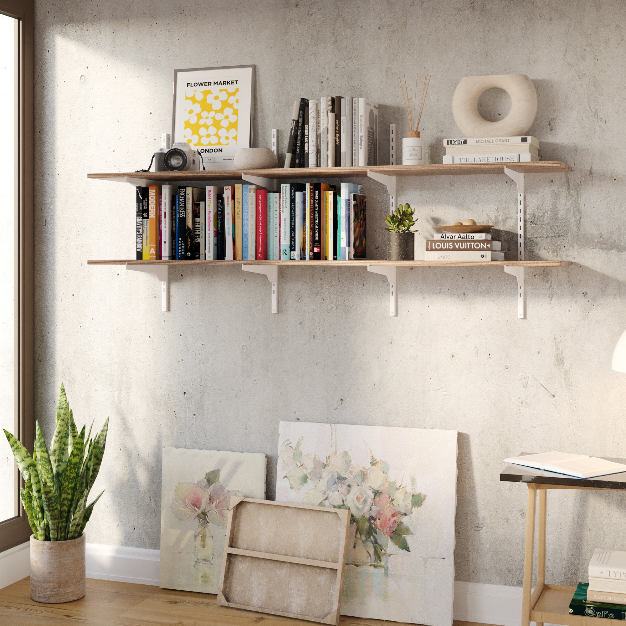 Two 60 inch long wall-mounted shelves with white rails and brackets, styled on a concrete wall with books, framed art, plants, and decor for a modern industrial look.