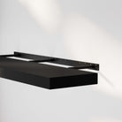 A foating shelf for wall black with an invisible bracket, mounted on the wall, highlighting its sleek design and sturdy brackets.