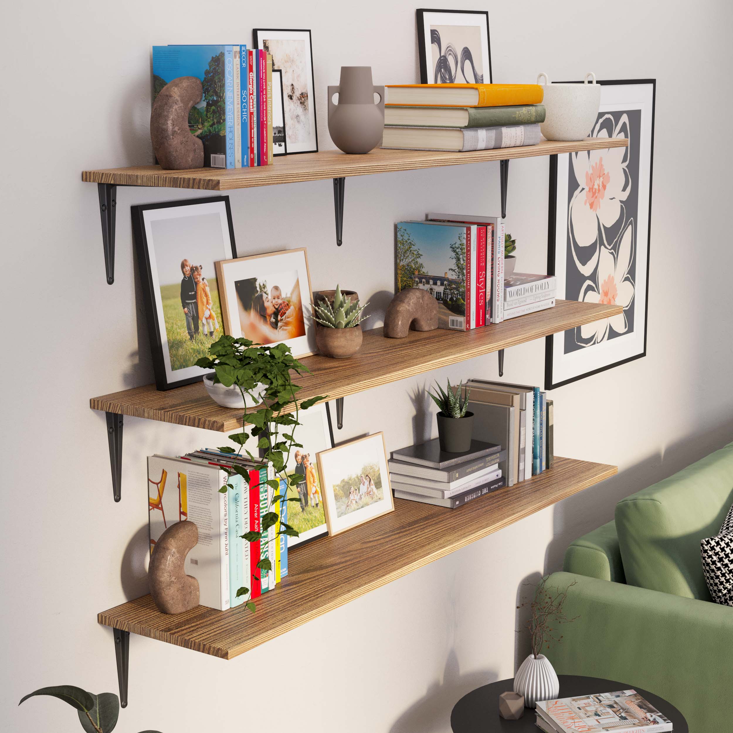 Three-tier floating shelf setup for living room featuring dark metal brackets and wood grain boards. Styled with books, family photos, vases, and small plants, it adds warmth and personality to a cozy living room with a green sofa.