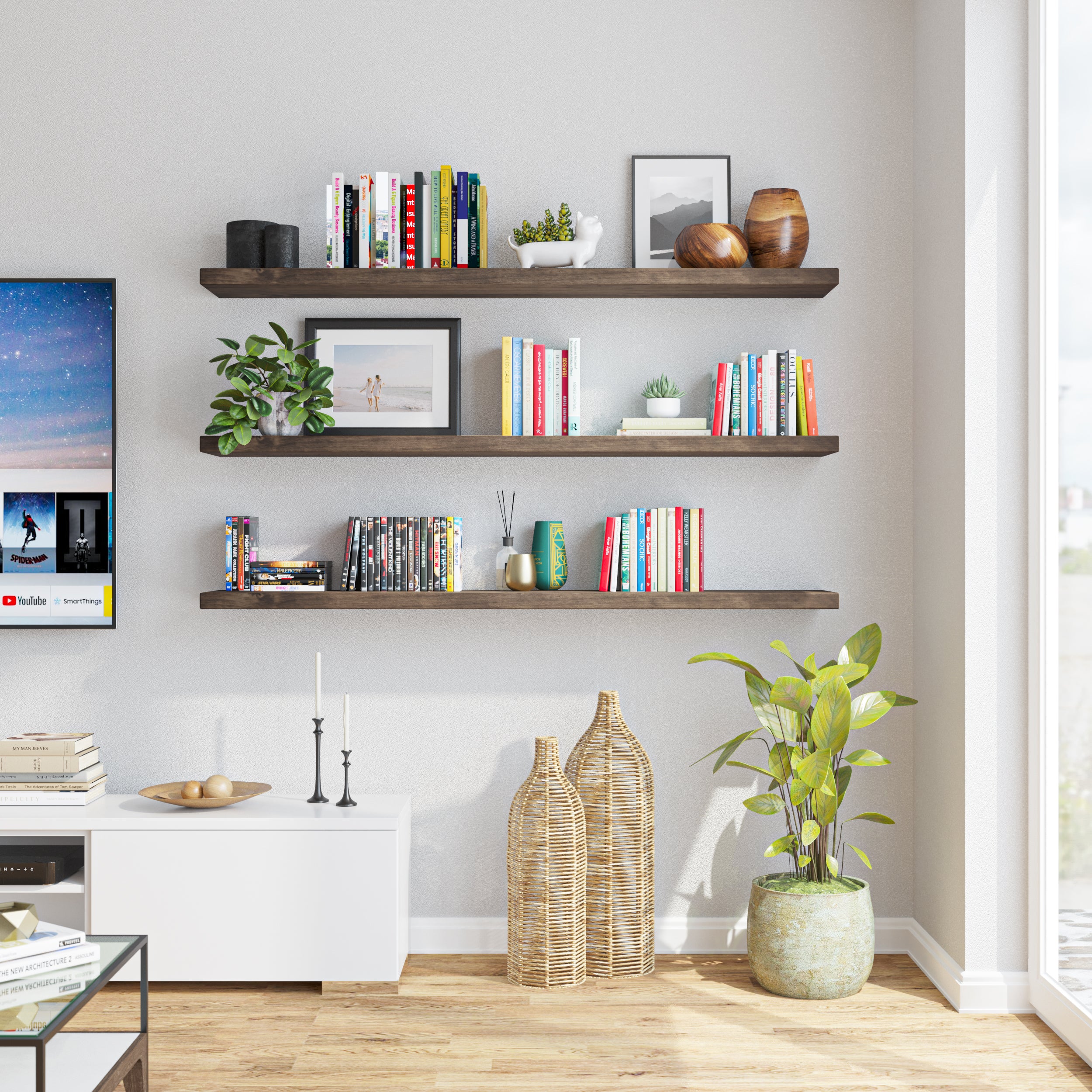 Three floating shelves for living room arranged vertically, filled with colorful books and small decorative pieces. Positioned next to a TV, it creates a functional and stylish living room setup.