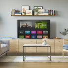 Multi-tiered shelving display showcasing books, framed art, and decor items in a cozy living room with a soft gray wall and elegant furniture.