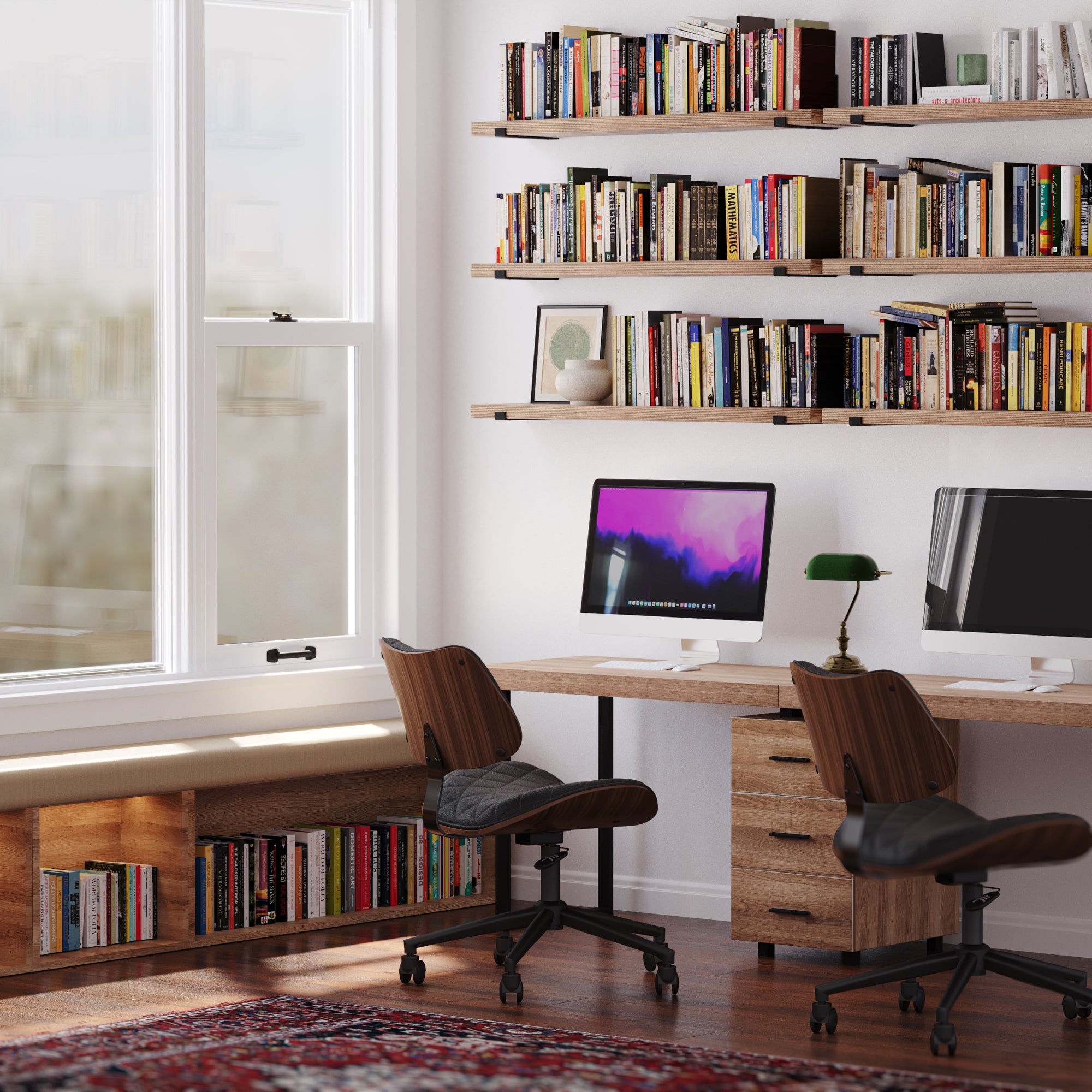 A modern office with wall bookshelves, books, computers, and warm lighting.