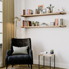 Two rustic display shelves with books and small decorative elements, positioned above a cozy reading chair.