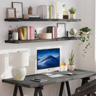 Two wooden office shelves with books and decorative objects above a black desk in a modern home office setup.