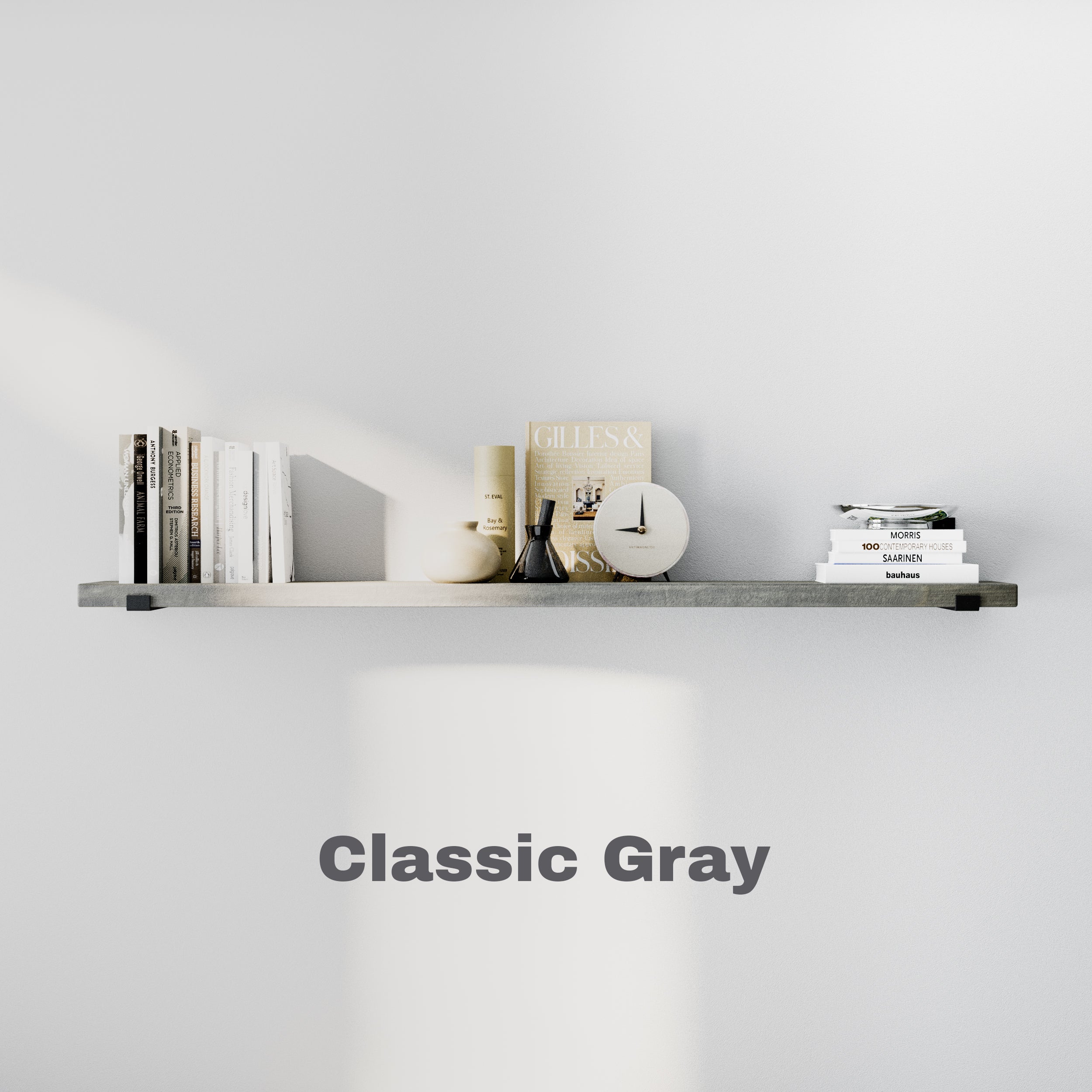 A long floating shelf in "Classic Gray" finish against a white wall. The shelf is minimally styled with books, a clock, and neutral decor. The text "Classic Gray" is displayed below.