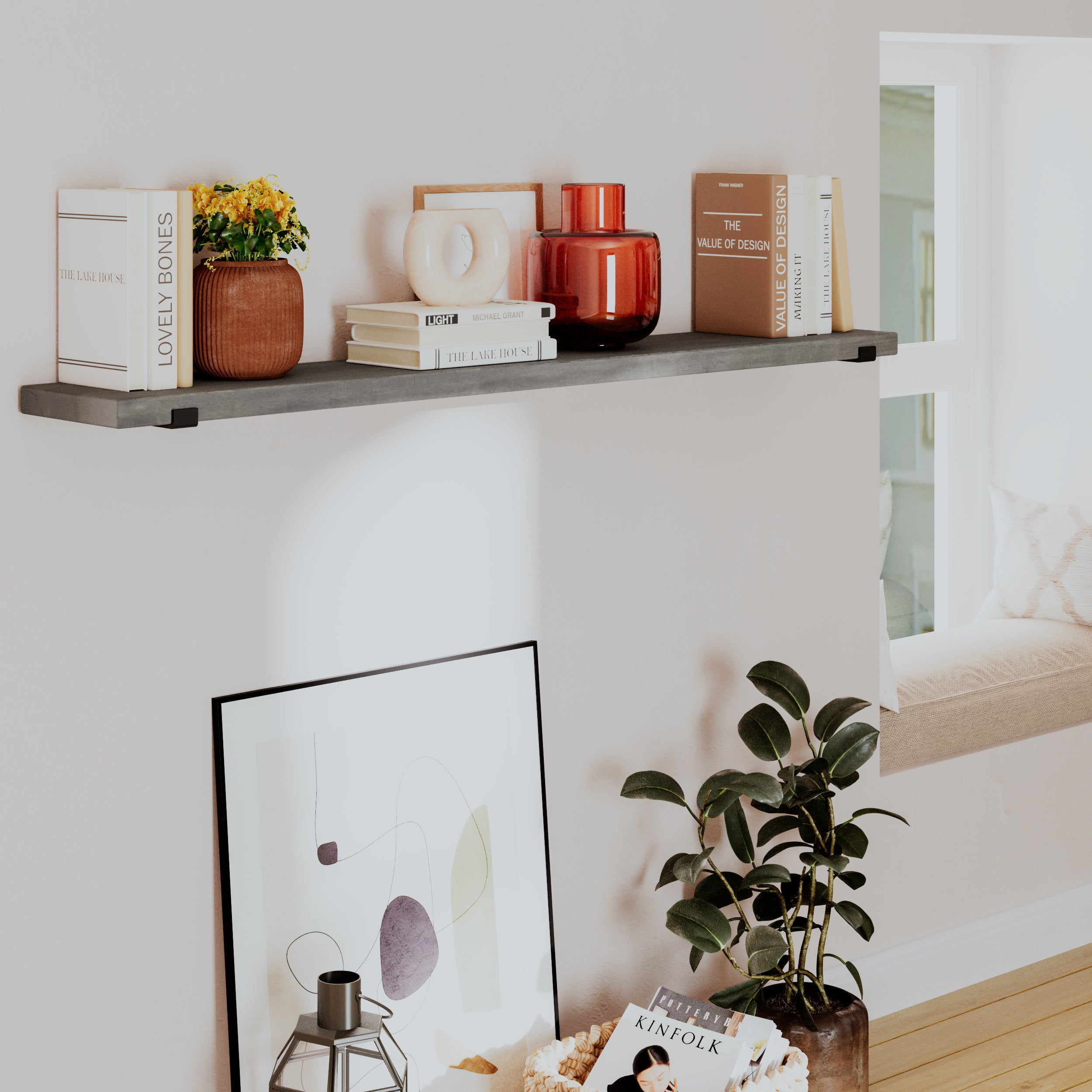 A "Classic Gray" long hanging shelf styled in a living space. It holds books, a vase with flowers, and modern decor elements. Below it, there's a framed artwork and a plant, contributing to a cozy, neutral aesthetic.