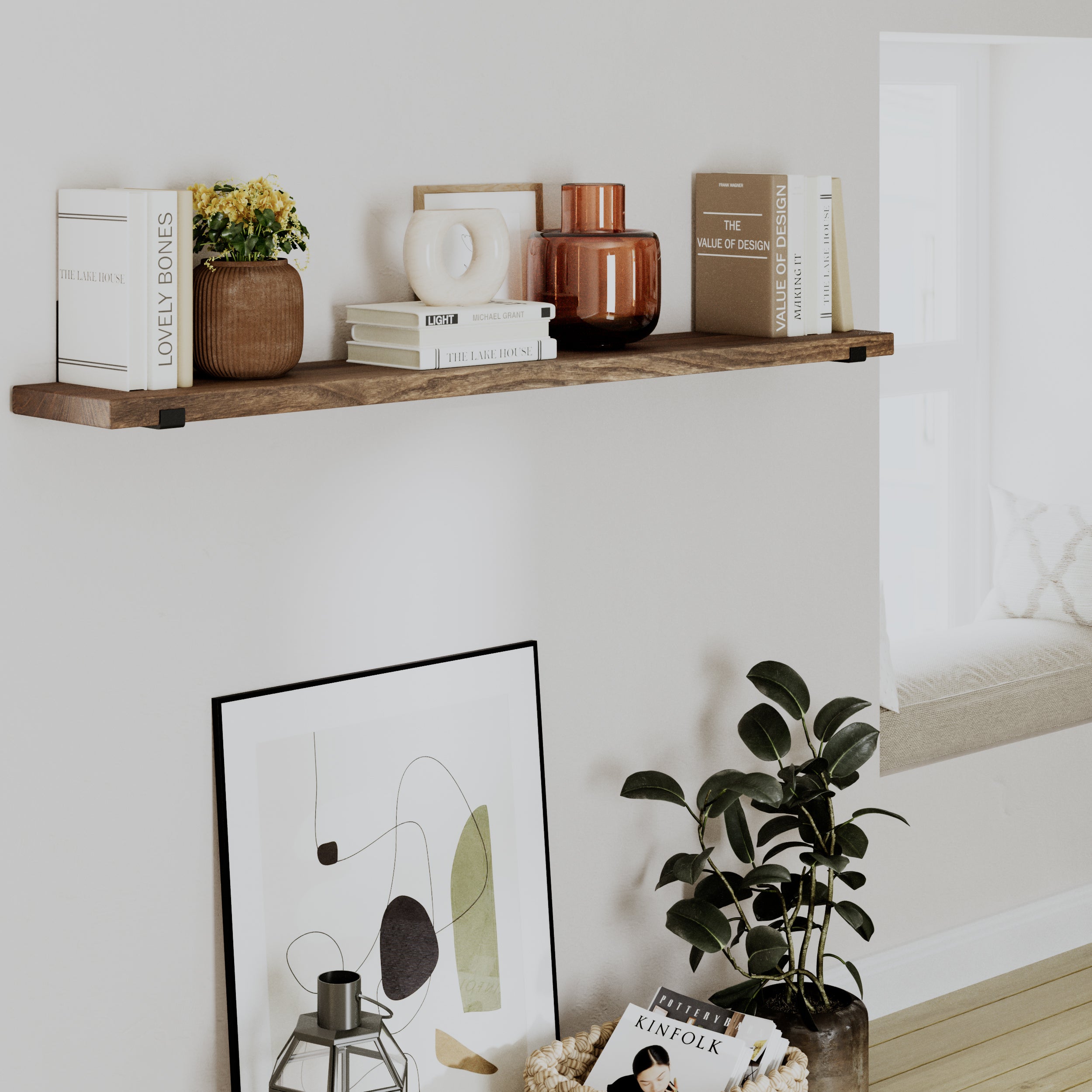 A single provincial wood shelf above a seating area, decorated with books, vases, and framed artwork. A green plant adds natural contrast.