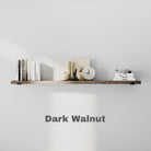 A floating bookshelf in dark walnut finish against a light wall, styled with books, a clock, and decorative items.