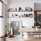 Two wall-mounted long shelves in special walnut finish above a dining table display modern decor, neutral books, and minimal art in a clean and stylish layout. Ideal for contemporary dining spaces.
