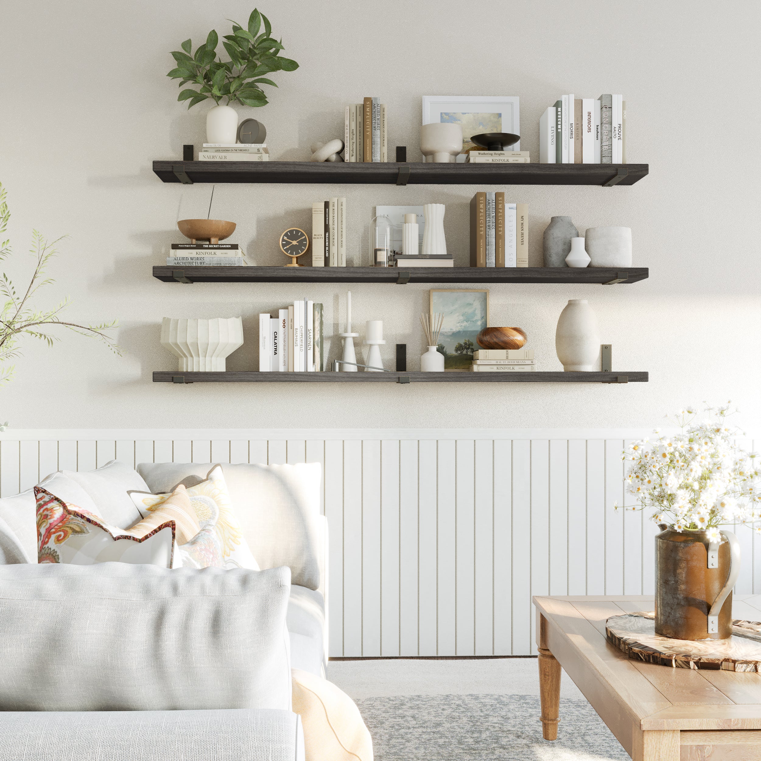 Three floating ebony shelves styled with books, frames, and ornaments, enhancing a cozy neutral-toned living room with contrast and elegance.