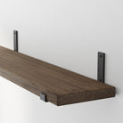 Wall-mounted Dark Walnut hanging shelf and minimalist black brackets. Highlights the wood’s grain and finish, showcasing the shelf’s durability and handcrafted character.