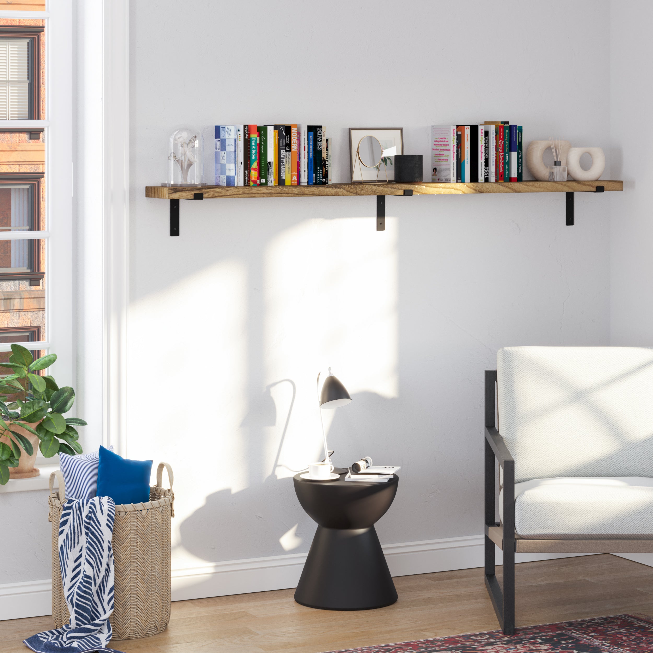 A single wall book shelf for storage above a black side table, adorned with books, a mirror, and decorative items in a sunlit modern space.