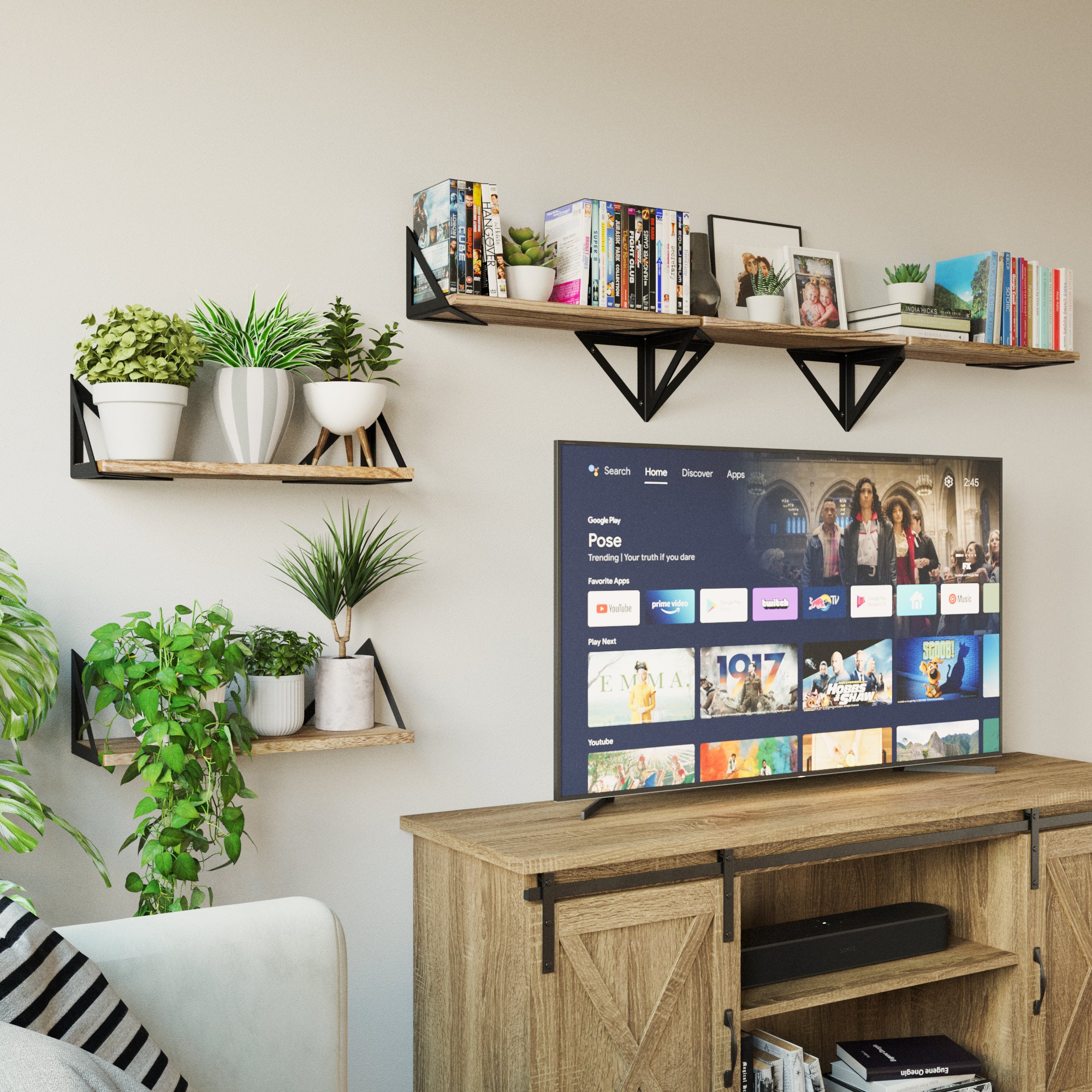 Living room with wall shelves supported by triangular black metal brackets, displaying books and plants.