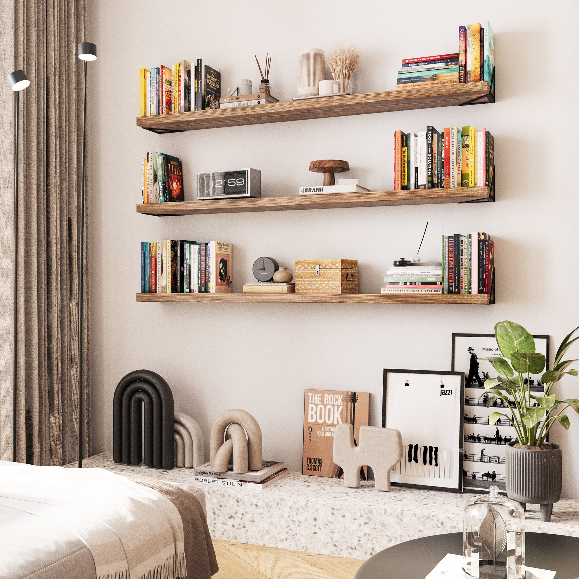 3 long bookshelves in a modern living space, displaying books, decor items, and small plants. The shelves are mounted on the wall, providing both storage and a stylish focal point in the room.