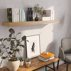A cozy corner with a 48 inch long rustic book shelf styled in an entryway or reading nook. Shows off decorative styling potential and natural wood tones that blend with indoor plants.