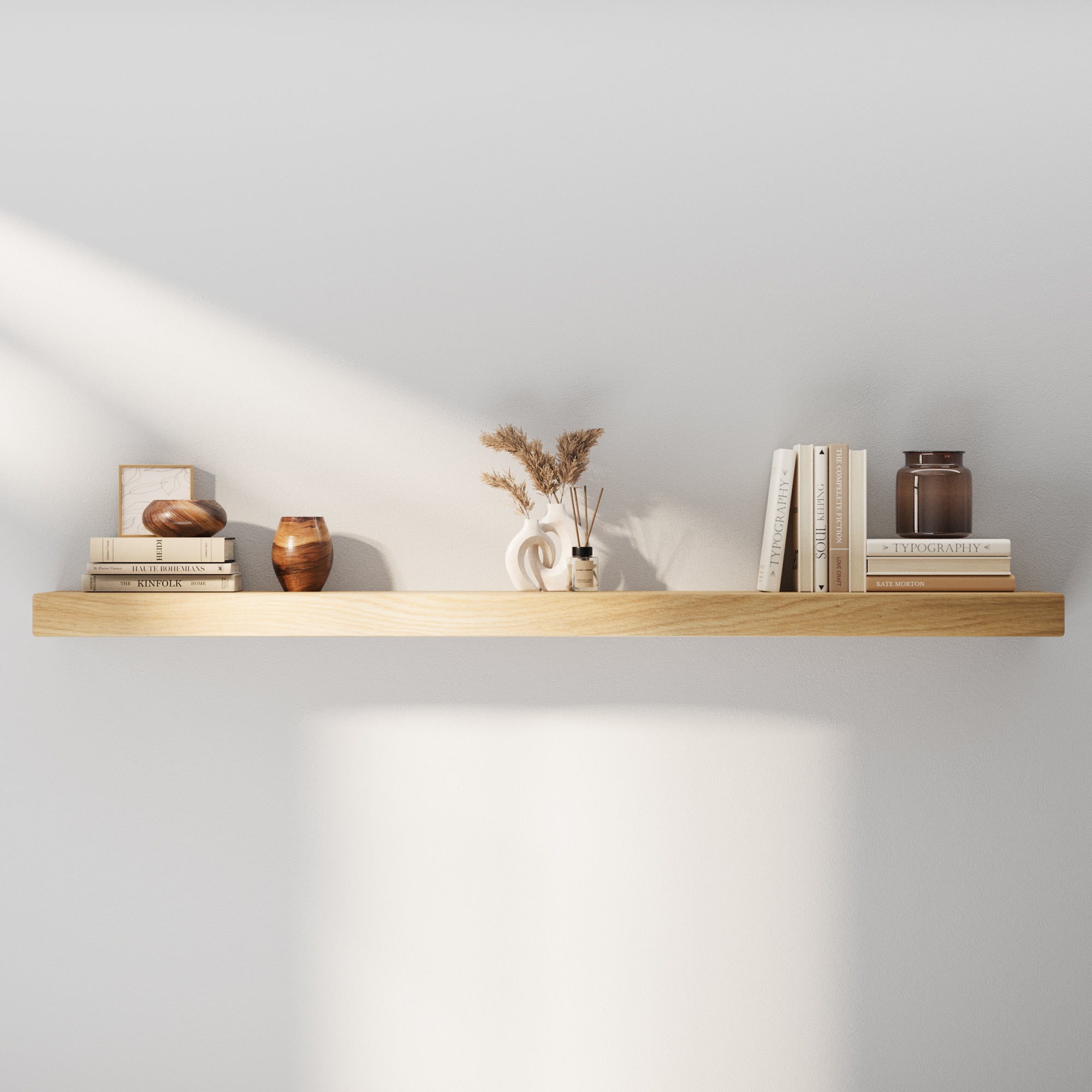 Minimalist 60 inch long wooden floating shelf styled with neutral books, vases, and décor. Highlights the natural white oak veneer finish and clean, seamless wall-mount design.