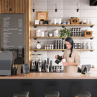 A modern coffee bar setup featuring coffee bar shelves holding mugs, jars, and plants, perfectly blending functionality with aesthetics.