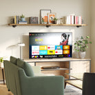 A cozy living room with a TV console, a long pipe bracket shelf above, styled with books, framed art, and planters for a contemporary vibe.