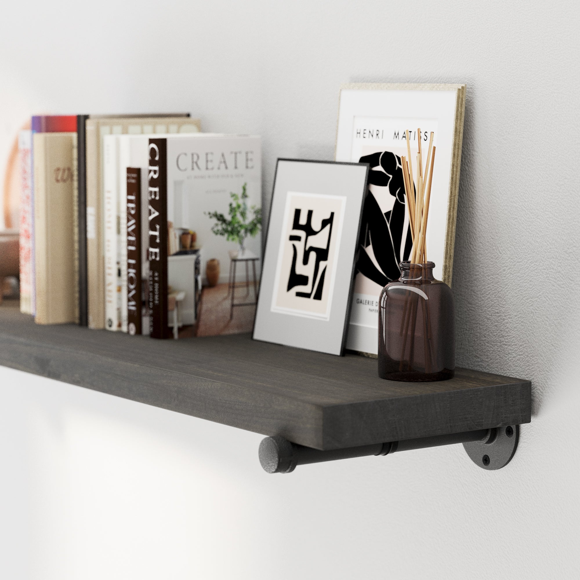 A 60 inch hanging shelf featuring rustic wood texture and durable metal pipe brackets. Styled with books, framed prints, and diffuser décor, ideal as a floating bookshelf, office shelf, or living room wall shelf.