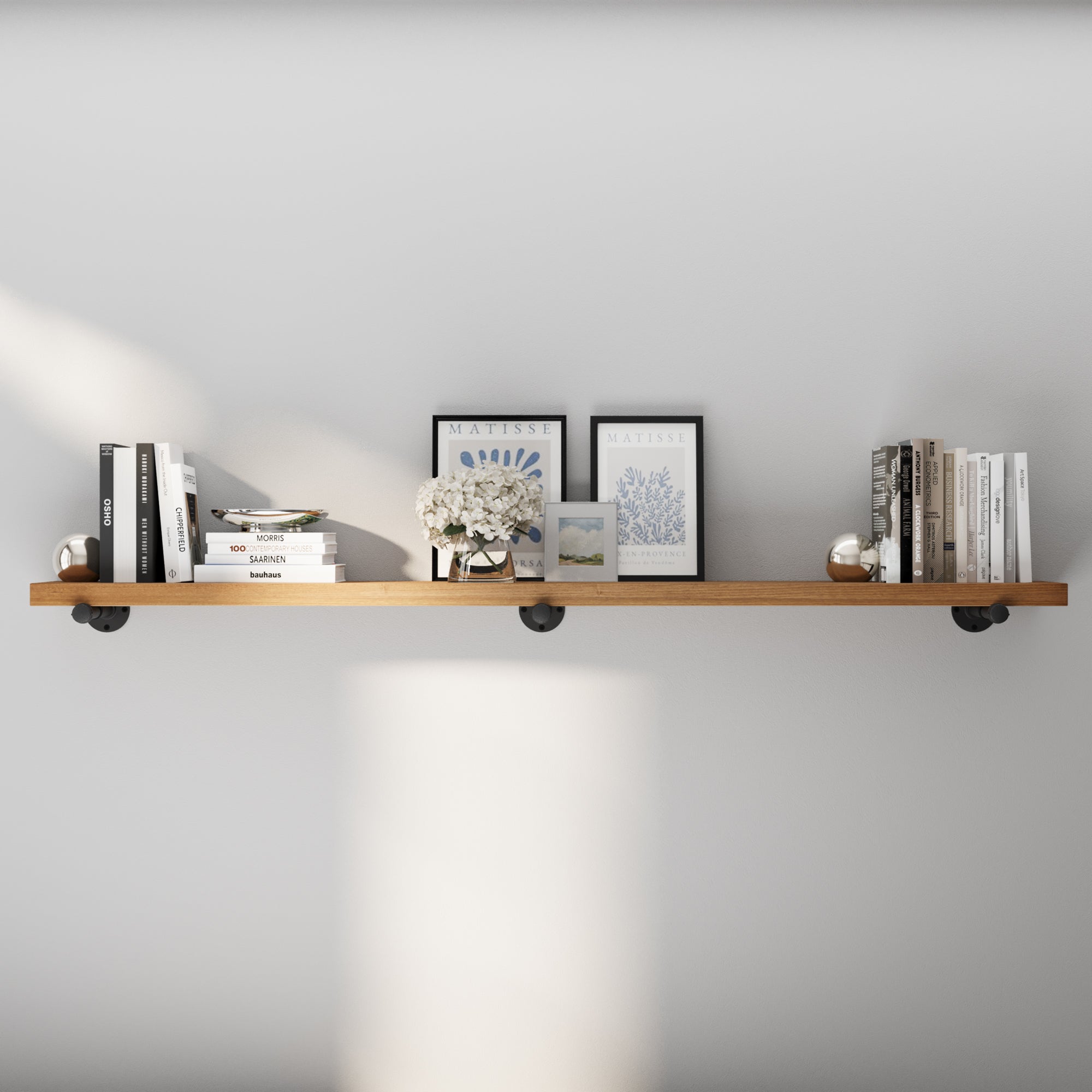 72 inch industrial pipe shelf with a rich Special Walnut finish, styled with books, framed art, and décor accents. This extra long wall shelf blends rustic warmth and modern industrial style for living room, office, or bedroom storage.