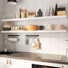 White kitchen wall shelf in a kitchen, organized with dishes, utensils, and kitchen tools.