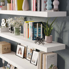 A modern home interior with white floating shelves elegantly decorated with books, photo frames, and plants. The clean and minimalist design offers both style and practical storage for showcasing personal items.