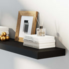 Close-up of a black floating shelf displaying books, a framed photo, and a diffuser, highlighting its sleek, minimalist design suitable for modern décor.