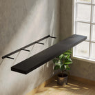 Installation view of a black shelf with a hidden bracket, showing its seamless floating design and sturdy, concealed support.