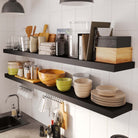 Close-up of kitchen storage shelves showcasing bowls, jars, and books, emphasizing the storage capacity and modern aesthetic of black floating shelves.