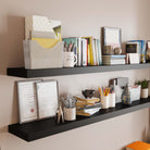 Close-up of two black hanging shelves displaying books, files, and office accessories, showcasing their ample space and sleek design perfect for organizing work essentials.