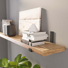 A stylish floating wood bookshelf supported with black metal L shaped industrial brackets against a gray wall.