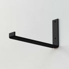 A single black rectangular shelf bracket mounted on a wall.