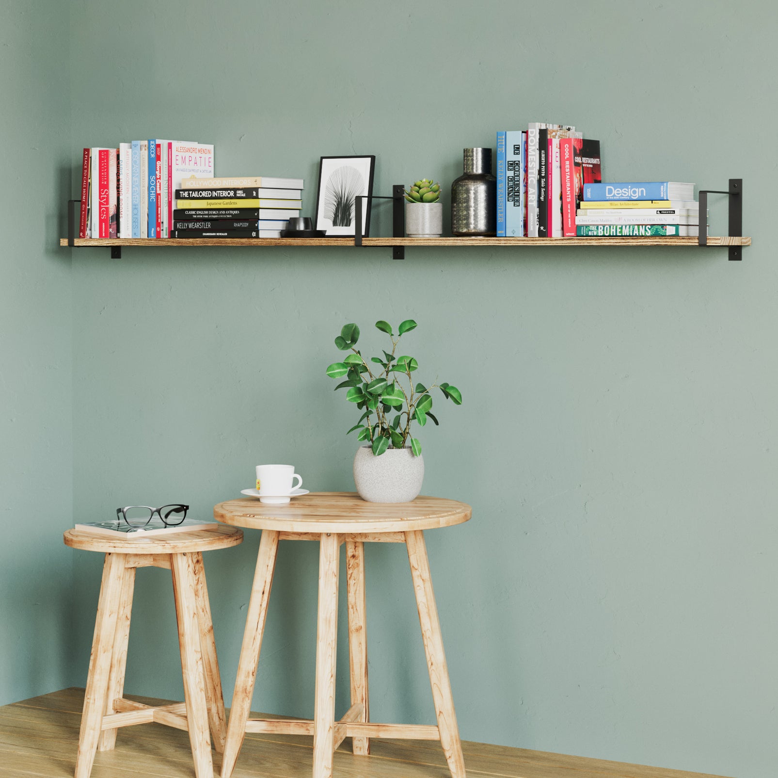 Long wood shelf pops against a green wall, holding an eclectic mix of colorful books and small plants. It pairs beautifully with the wooden stools and cozy coffee corner below.