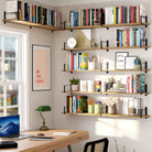 A stylish office space with multiple wall-mounted office shelves wrapping around the corner, filled with colorful books, decorative elements, and motivational wall art, enhancing productivity and organization.
