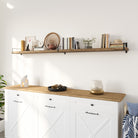 A single hanging shelf with dark brackets sits above a white farmhouse-style cabinet. It holds a mix of vases, books, and decor, blending rustic and modern for a warm, inviting touch.