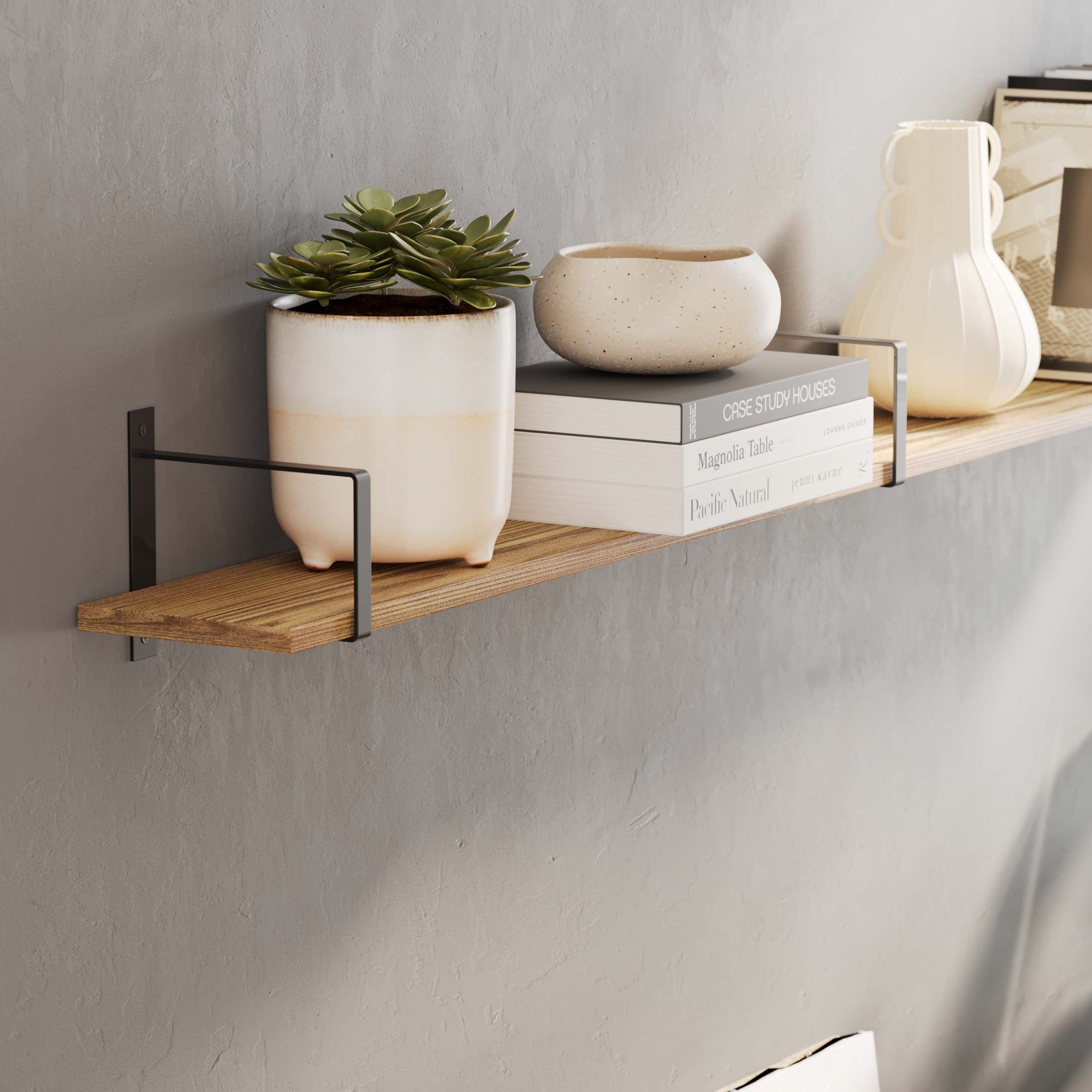 Wooden long shelf with decor items supported by black rectangular shelf brackets in a living room.
