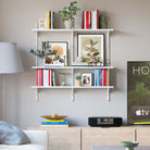A tidy home office space with white shelves displaying books and decor.