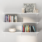 A modern white 3-tier wall bookshelf mounted on adjustable metal tracks, styled with books and decor for a clean and organized wall setup.