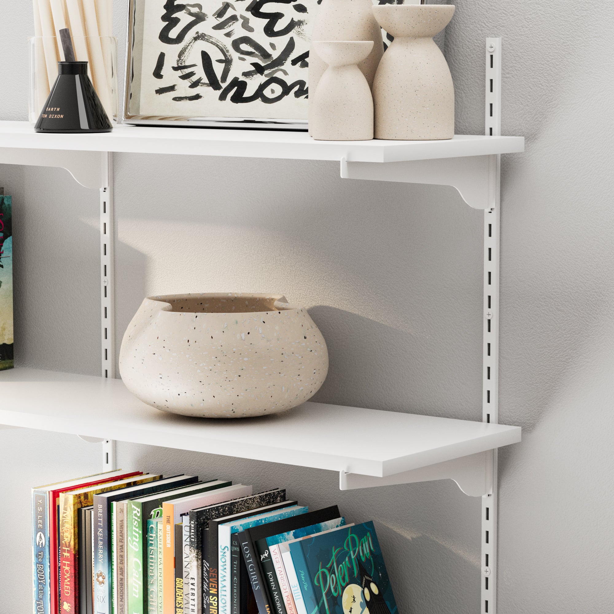 The adjustable shelf’s edge, showing its sturdy bracket support and stylish decor like ceramics and framed artwork.