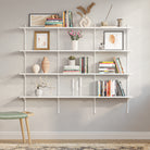 A clean, empty 4-tier wall-mounted shelving unit with white metal rails and adjustable brackets, ready to be customized for books, decor, or storage