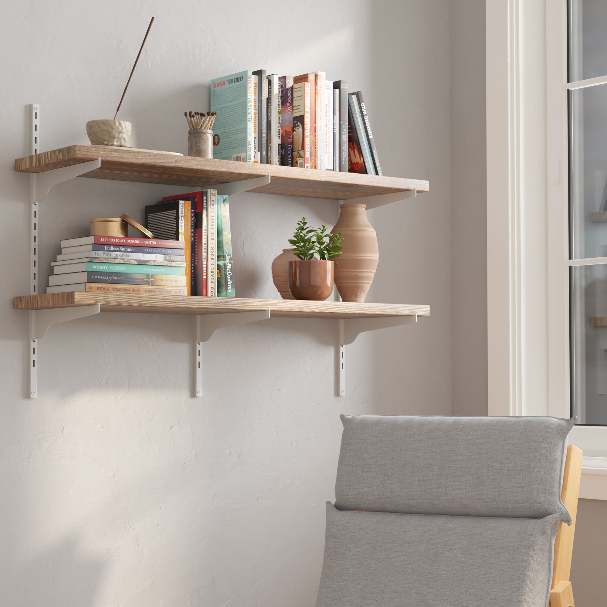 36 inch long 2 tier floating bookshelves with books and decor items against a white wall, with a chair in the foreground.